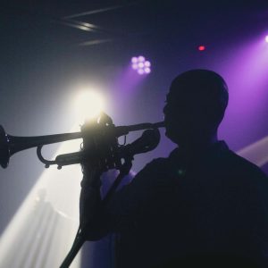 A captivating silhouette of a musician playing a trumpet under vibrant concert lights.