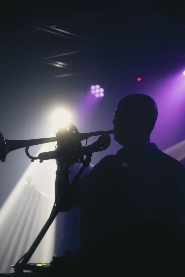 A captivating silhouette of a musician playing a trumpet under vibrant concert lights.