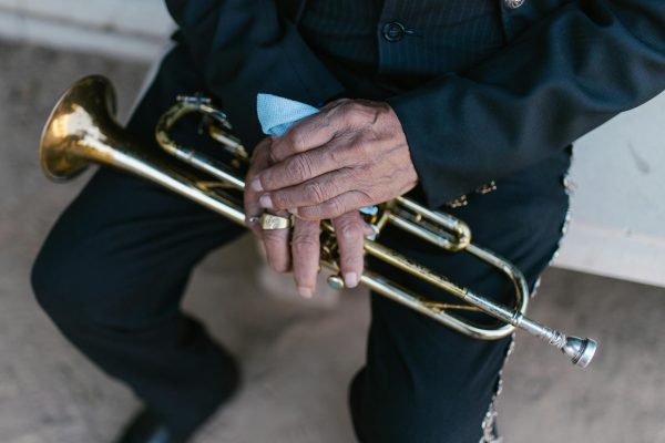 An adult musician holding a brass trumpet, focused on hand details and instrument.