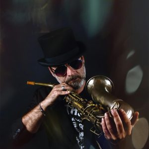 Portrait of a stylish jazz musician in sunglasses playing the trumpet indoors.