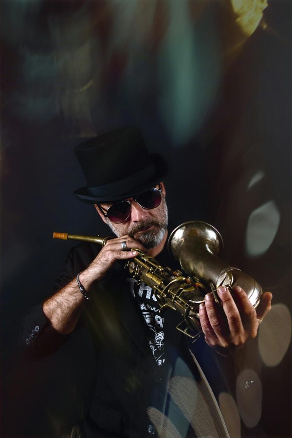 Portrait of a stylish jazz musician in sunglasses playing the trumpet indoors.